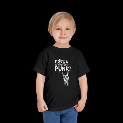 A young child with blonde hair is standing and smiling, wearing a black short sleeve toddler tee that boldly states MOOGA IS THE NEW PUNK! in white. The graphic tee features a hand making a rock and roll gesture against a completely black background.