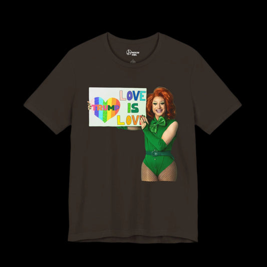 The Trump-Love Tee is a black unisex jersey showcasing a vibrant illustration of a drag queen in green, holding a rainbow sign declaring Love is Love, complete with the word Trump inside a heart design.