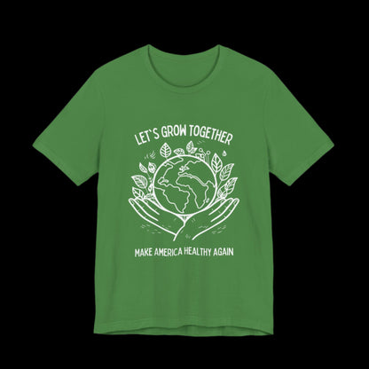 a leaf green unisex cotton shirt with a white graphic of a pair of hands holding the earth. In the background leaves surround, above and below the text LET"S GROW TOGETHER and MAKE AMERICA HEALTHY AGAIN