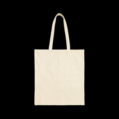 A natural white cotton canvas tote bag with two handles against a solid black background, subtly hinting at inclusivity with its stylish design.