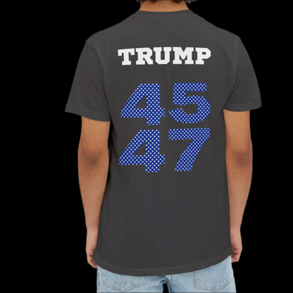 A man is sporting a garment-dyed black T-shirt emblazoned with TRUMP in bold white letters, complemented by 45 47 in blue polka dots on the back. This eye-catching top, reminiscent of sports jersey T-shirts, pairs well with their light blue jeans.