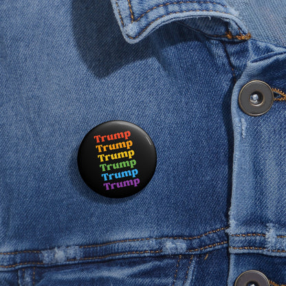 A denim jacket showcases a round metal with Mylar face button, featuring the word Trump repeated in rainbow colors—red, orange, yellow, green, and purple—vertically displayed as an eye-catching nod to LGBTQ Pride.