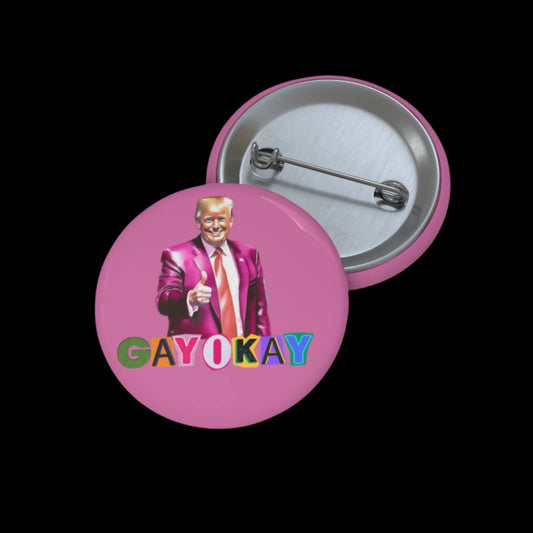 A pink button featuring a suited Donald Trump giving a thumbs-up. The text GAY OKAY appears in colorful, bold letters, celebrating Trump Pride and LGBTQ unity. Another button is shown from the back, displaying a pin mechanism.