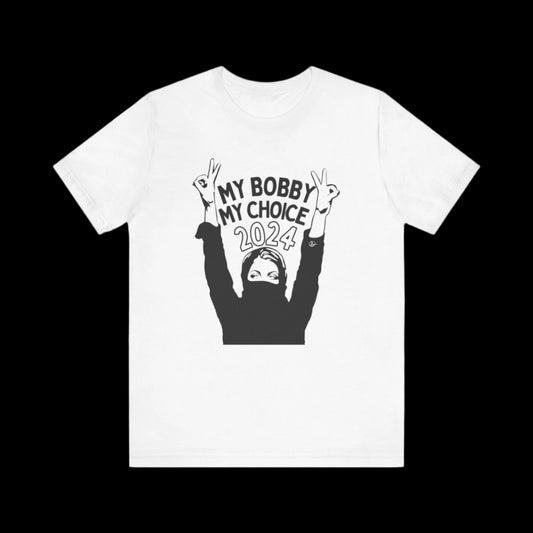 A white jersey short sleeve t-shirt showcasing a graphic of a woman with raised hands flashing peace signs. The text reads, “MY BOBBY MY CHOICE 2024.” Perfect as a unisex tee for expressing your style and support for RFK Jr.