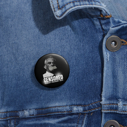 A black and white pin button on a denim jacket showcases an image of RFK Jr.'s face with Kennedy Censored and Kentucky President 2024 inscribed beneath. The jacket, adorned with metal buttons, is light blue in color.