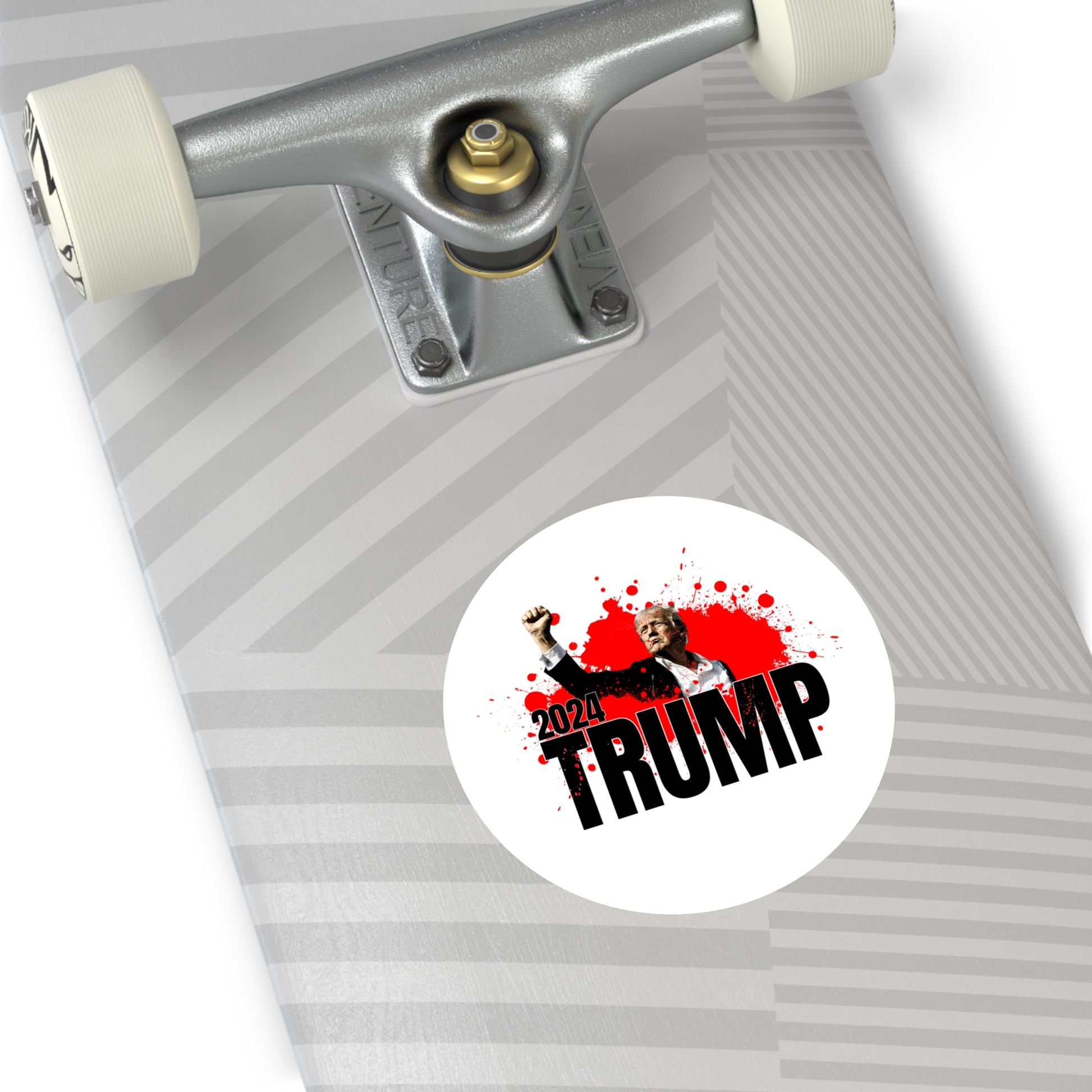 A skateboard adorned with a geometric design features a bold premium vinyl sticker of Trump raising a fist. The 2024 TRUMP sticker stands out with red ink splatter graphics, capturing attention effortlessly.