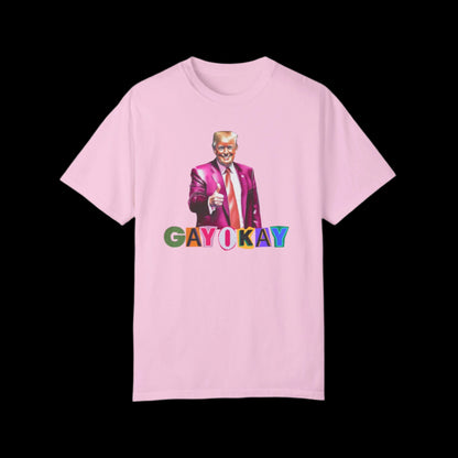 Unisex blossom pink cotton T-shirt featuring a graphic of a person in a pink suit, pointing forward. Below, the text reads GAY OKAY in colorful letters. This bold LGBTQ design is set against a striking black background.