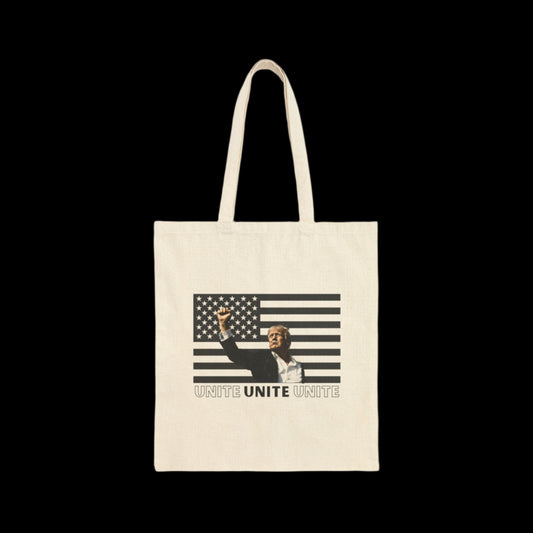 This 15” x 16” 100% cotton canvas tote bag showcases an illustration of Donald Trump raising his fist against a backdrop of a stylized black-striped American flag. At the bottom, UNITE is boldly repeated three times, capturing the spirit of unity in this eye-catching Trump American Flag Tote Bag.