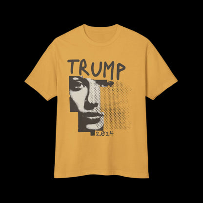 A garment-dyed faded mustard yellow T-shirt features a stylized black and white portrait of a face, partially pixelated, with TRUMP above and 2024 below. This vintage-style design is set on a black background, crafted from 100% cotton for maximum comfort.