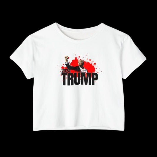 The Womens-Trump-Fist Pump-2024-Festival-Crop Top features a graphic of a person raising a Trump fist against a red splatter backdrop and bold black text reading 2024 TRUMP, perfect for festivals and expressing your political enthusiasm.